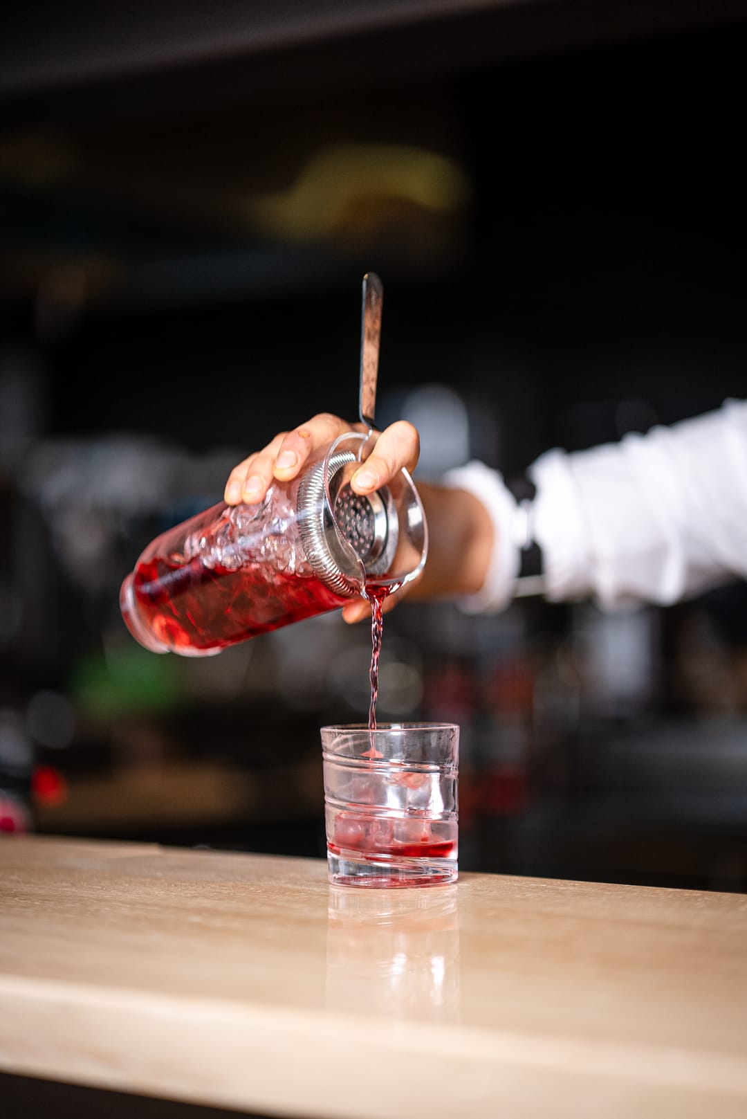 Barmen karıştırma bardağından kokteyli süzüyor